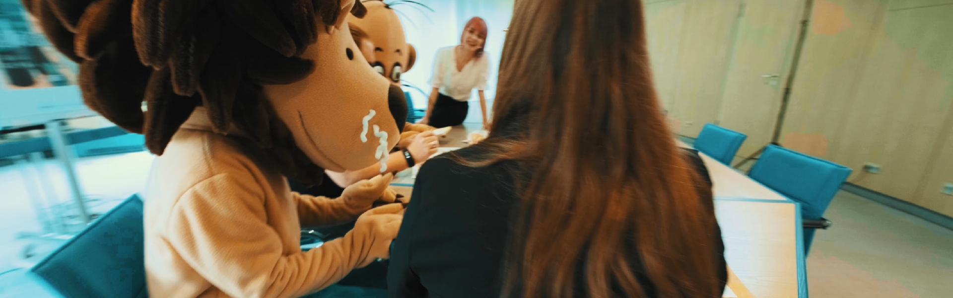 Der Leselöwe mit Mitarbeiter*innen an einem Tisch im Besprechungsraum