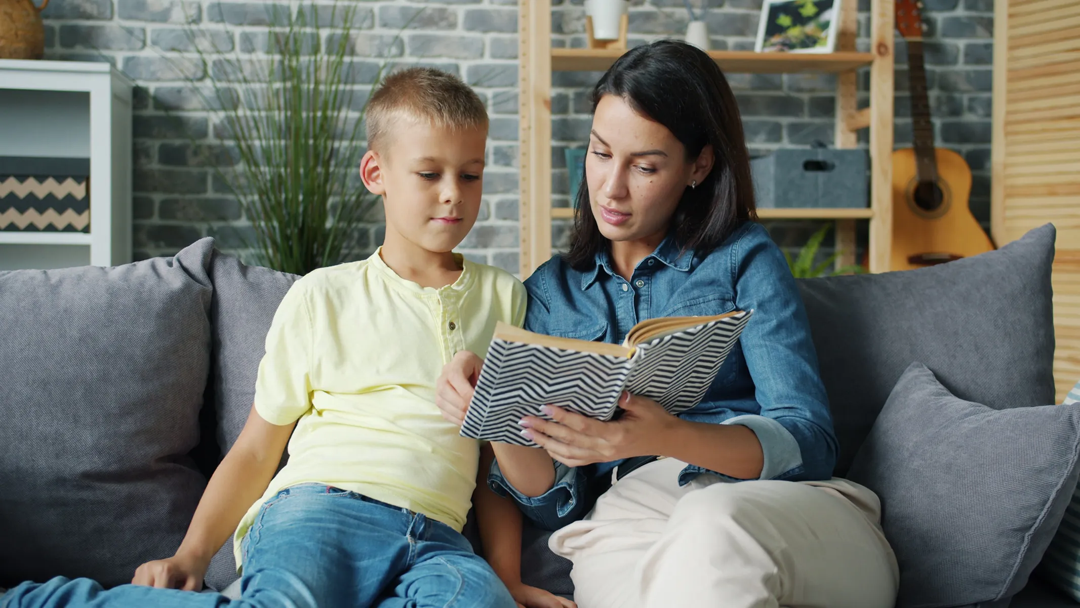 Foto einer Mutter, die mit ihrem Kind ein Buch liest
