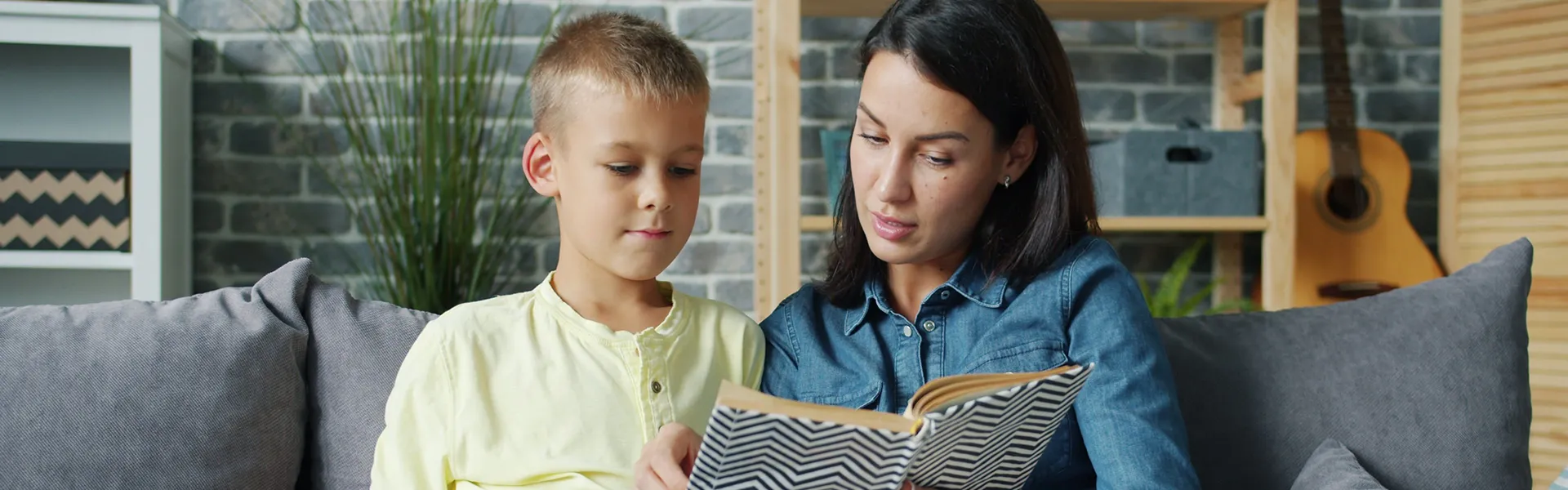 Foto einer Mutter, die mit ihrem Kind ein Buch liest